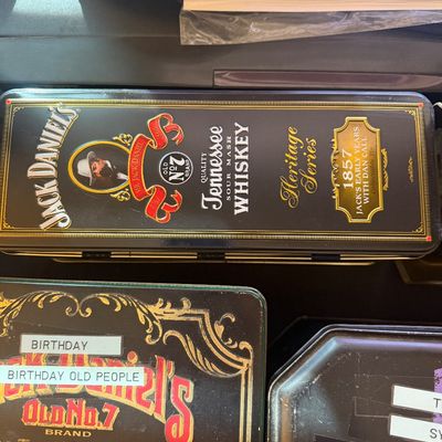 Sale Photo Thumbnail #317: Jack Daniel's Heritage Series 1857 collectible tin alongside other branded tins.