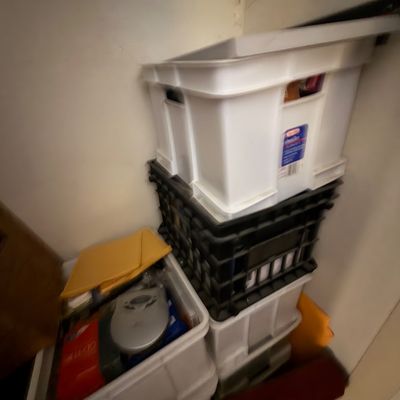 Sale Photo Thumbnail #112: Stack of white plastic storage totes and black milk crates containing assorted household items and media, including a portable CD player.