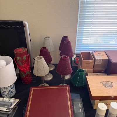 Sale Photo Thumbnail #192: Collection of tabletop decor and collectibles including miniature beaded lamp shades, wooden cigar boxes, a red photo album, and a small ceramic lamp.