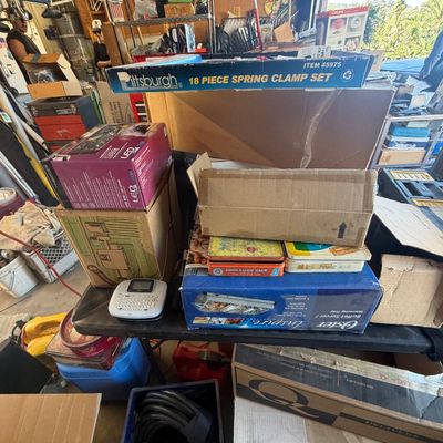 Sale Photo Thumbnail #215: Assorted household goods, tools, and electronics organized on tables in a garage sale setup.