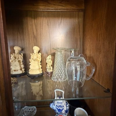 Sale Photo Thumbnail #149: Collection of decorative glassware and resin Oriental figurines displayed inside a wooden hutch.