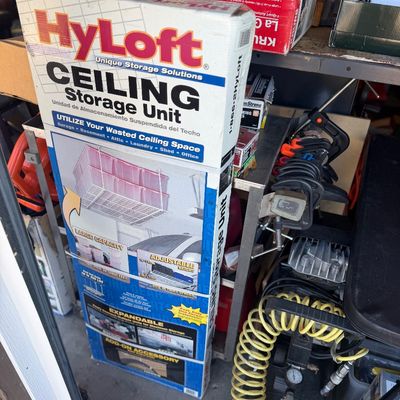 Sale Photo Thumbnail #55: Vintage HyLoft ceiling storage unit in original box, shown alongside a small portable air compressor and assorted garage tools.