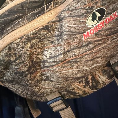 Sale Photo Thumbnail #13: Mossy Oak camouflage waist pack featuring an embroidered logo, multiple zippered compartments, and adjustable straps.