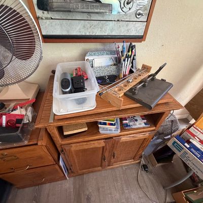 Sale Photo Thumbnail #96: Vintage oak TV stand media cabinet holding various office supplies, a shoot-the-moon game, and paper cutter.