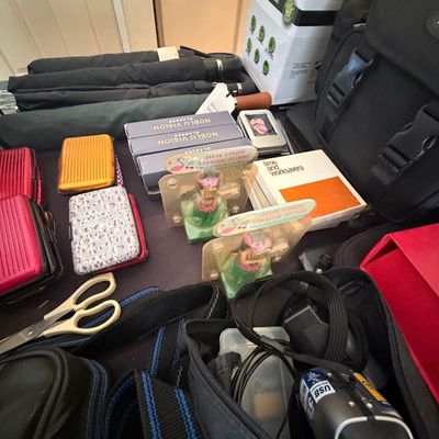 Sale Photo Thumbnail #102: Assortment of modern household goods, including compact umbrellas, aluminum card wallets, solar hula dancer novelties, camera bags, and small electronics.