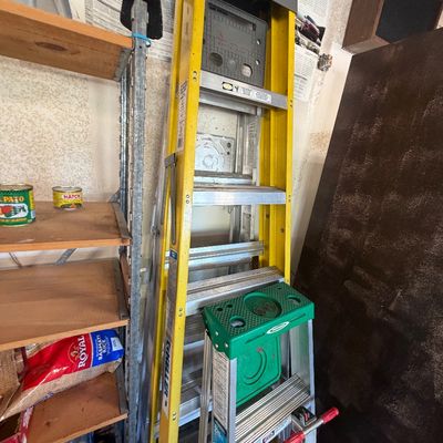 Sale Photo Thumbnail #44: Keller yellow fiberglass stepladder standing alongside a smaller aluminum step stool in a garage setting.