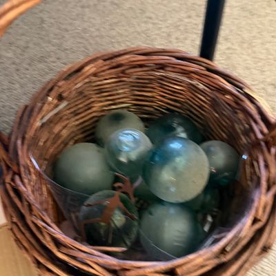 Sale Photo Thumbnail #31: Collection of aqua glass fishing floats housed inside a round woven wicker basket.