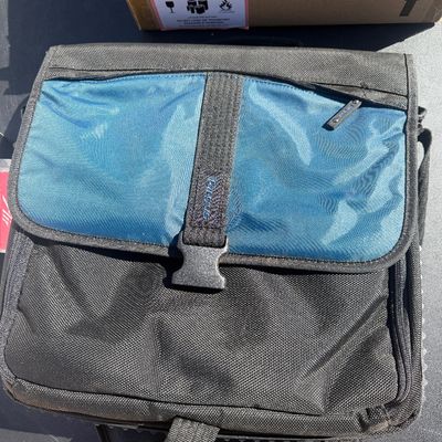Sale Photo Thumbnail #292: Targus laptop shoulder bag in black and teal nylon, featuring a front quick-release buckle and zippered compartment.