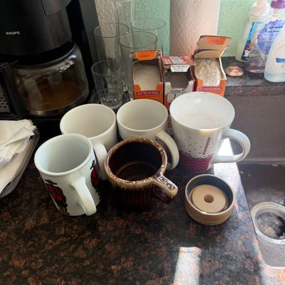 Sale Photo Thumbnail #20: Collection of coffee mugs including a Starbucks mug, a vintage brown drip glazed mug, and plain white ceramic mugs displayed on a kitchen counter near a Krups coffee maker.