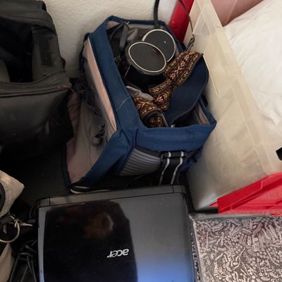Sale Photo Thumbnail #199: Black Acer netbook computer alongside a blue camera bag filled with lenses and accessories.