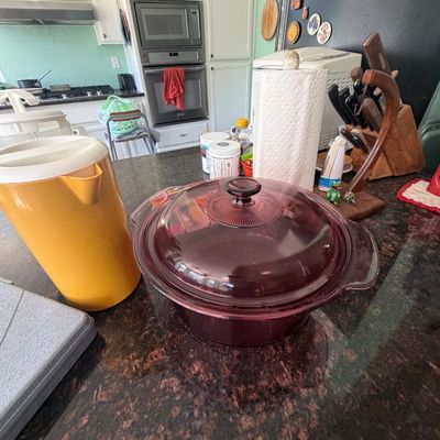 Sale Photo Thumbnail #90: Vintage Visions cranberry glass casserole dish with lid, displayed on a granite countertop alongside a vintage yellow pitcher.