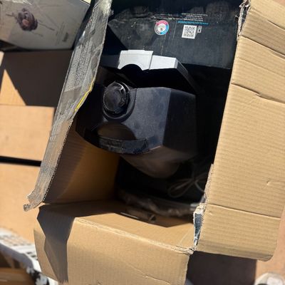 Sale Photo Thumbnail #260: Black electronics device, likely a printer or small appliance, packed inside an open cardboard box.