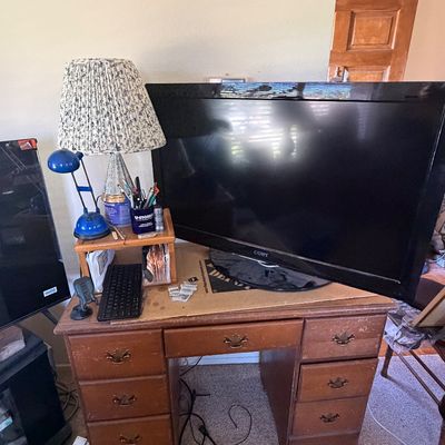 Sale Photo Thumbnail #129: Vintage wood pedestal desk with a Coby flat-screen television, table lamps, and desk accessories.
