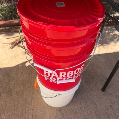 Sale Photo Thumbnail #290: Stack of 5-gallon plastic utility buckets, including red Harbor Freight buckets with wire metal handles.