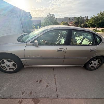 Sale Photo Thumbnail #5: Early 2000s gold Chevrolet Impala four-door sedan parked in a residential driveway.