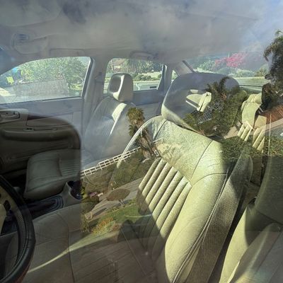 Sale Photo Thumbnail #6: Interior view of a sedan showing light tan leather front bucket seats, seen through a tinted window.