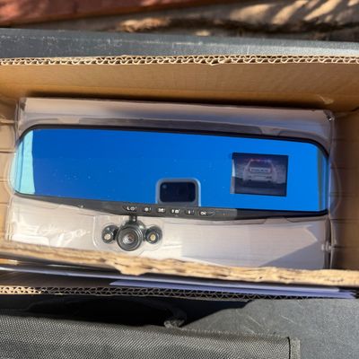 Sale Photo Thumbnail #281: Rearview mirror dash camera with a built-in display screen, resting in its original open cardboard box.