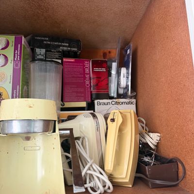 Sale Photo Thumbnail #14: Collection of vintage kitchen appliances and accessories inside a cabinet, including an electric juicer, hand mixer, and boxed gadgets.