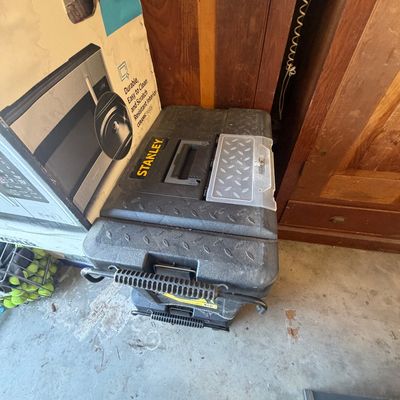 Sale Photo Thumbnail #216: Stanley mobile tool chest in heavy-duty molded black plastic, sitting on a concrete garage floor next to boxed appliances.