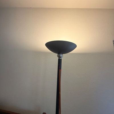 Sale Photo Thumbnail #303: Contemporary black and brushed metal torchiere floor lamp, illuminated and showing minor signs of use.
