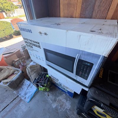 Sale Photo Thumbnail #217: Samsung over-the-range microwave oven in original cardboard packaging.