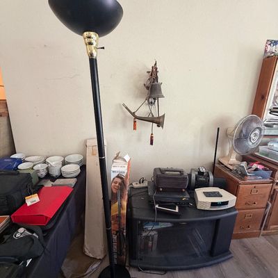 Sale Photo Thumbnail #103: Black metal torchier floor lamp with brass accents standing next to a black media console holding electronics and a Bose Wave radio.