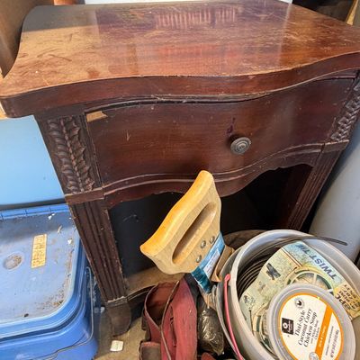 Sale Photo Thumbnail #210: Vintage mahogany nightstand featuring carved corner pillars, a single serpentine drawer, and an open lower shelf, showing surface wear and finish loss.