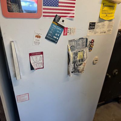 Sale Photo Thumbnail #206: White Whirlpool upright freezer featuring magnetic notes, stickers, and a small mirror attached to the front door.