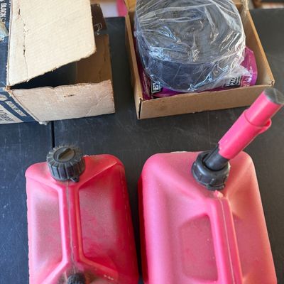 Sale Photo Thumbnail #249: Two red plastic gasoline cans alongside boxed automotive parts and accessories.