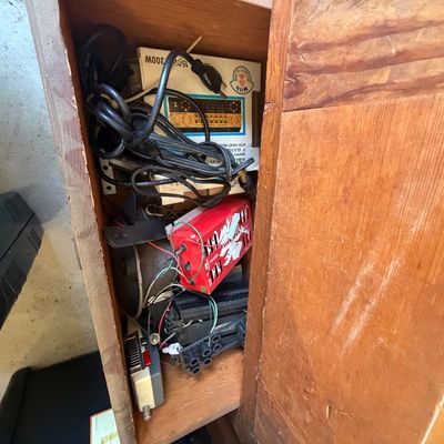 Sale Photo Thumbnail #232: Vintage wooden cabinet filled with assorted electronics, audio components, power cords, and boxed equipment.