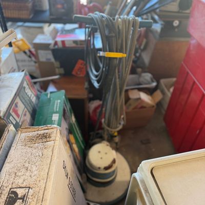 Sale Photo Thumbnail #47: Vintage heavy-duty commercial floor buffer with wrapped power cord surrounded by packed storage boxes and lawn tools.