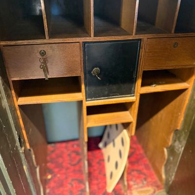 Sale Photo Thumbnail #203: Interior view of an antique safe or roll-top desk, featuring wooden compartments, small drawers with keys inserted, a central black lockbox, and a red patterned fabric lining.