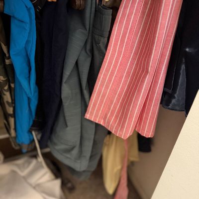 Sale Photo Thumbnail #177: Selection of men's clothing items including pants and shirts hanging in a closet.