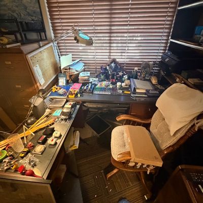 Sale Photo Thumbnail #117: L-shaped wooden home office desk setup with an upholstered swiveling desk chair, desktop magnifying lamp, office supplies, and small collectibles.