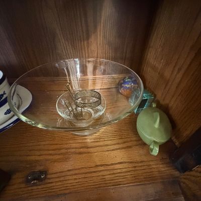Sale Photo Thumbnail #147: Collection of glass and ceramic shelf decor, including a clear glass pedestal bowl, a small green ceramic lidded jar, and decorative glass paperweights.