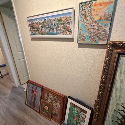 Sale Photo Thumbnail #120: Collection of wall art and framed prints, including a California pictorial map poster, landscape art, and a Joffrey Ballet poster, displayed along a hallway wall.