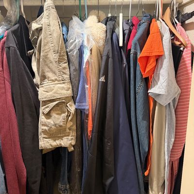 Sale Photo Thumbnail #184: Assorted men's and women's modern clothing including jackets, shirts, pants, and denim hanging in a closet.