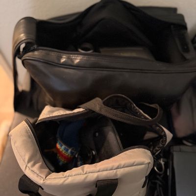 Sale Photo Thumbnail #200: Selection of padded camera carrying bags, including a beige canvas tote and a larger black leatherette case filled with gear.