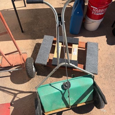 Sale Photo Thumbnail #266: Vintage green walk-behind lawn fertilizer spreader, shown outdoors alongside moving dollies.