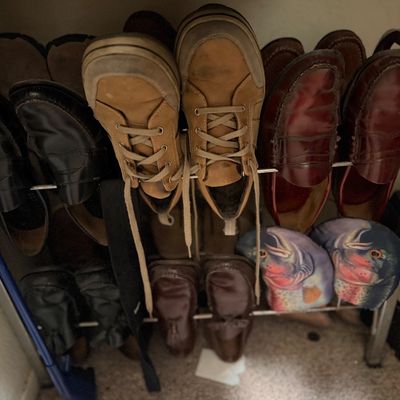 Sale Photo Thumbnail #179: Metal shoe rack filled with various men's footwear including leather loafers, casual sneakers, and novelty fish slippers.