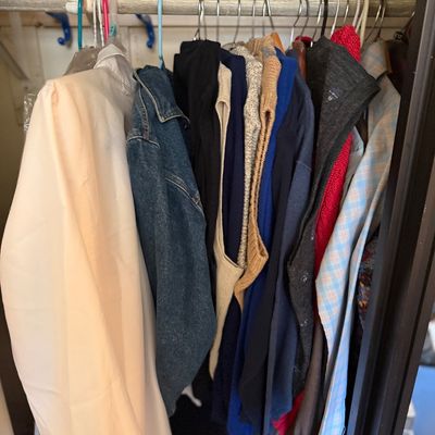 Sale Photo Thumbnail #172: Selection of vintage and modern women's clothing, including jackets, sweaters, and blouses hanging on a closet rack.