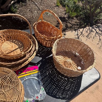 Sale Photo Thumbnail #286: Collection of woven wicker baskets in various shapes and sizes alongside a packaged toy jewel heart necklace.