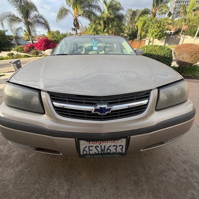 Sale Photo Thumbnail #2: Front view of a gold early-2000s Chevrolet Impala sedan, featuring noticeable paint oxidation and wear on the hood.