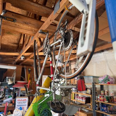 Sale Photo Thumbnail #49: Vintage Raleigh 10-speed road bicycle with a white and red frame suspended upside down from wooden garage rafters.