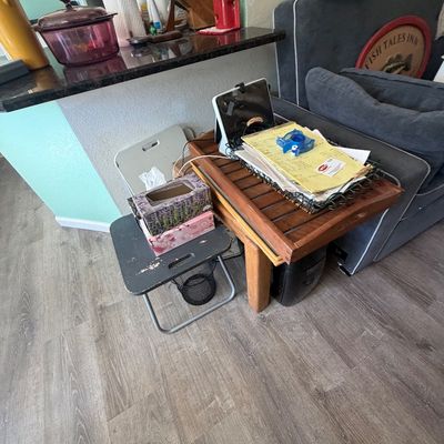 Sale Photo Thumbnail #91: Wooden slatted side table, small folding stool, and assorted desk accessories including a paper tray and tablet stand in a living area.