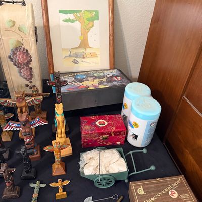 Sale Photo Thumbnail #158: Collection of tabletop items including carved wooden souvenir totem poles, framed artwork, a Discwasher record cleaning system, and small decorative boxes.