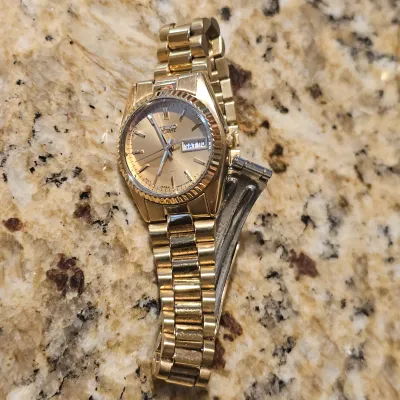 Sale Photo Thumbnail #94: Vintage gold-tone Seiko quartz watch featuring a fluted bezel, champagne dial, and day-date display window.