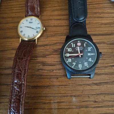 Sale Photo Thumbnail #47: Two men's wristwatches, featuring a gold-tone Seiko quartz watch with a brown leather strap and a Wenger Swiss Military watch with a black case and strap.