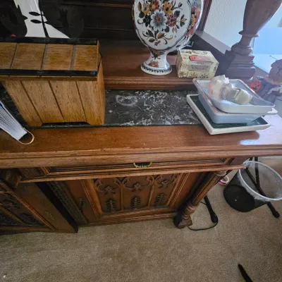 Sale Photo Thumbnail #98: Antique carved wooden sideboard or buffet featuring intricate paneling and a dark marble insert on the surface top.
