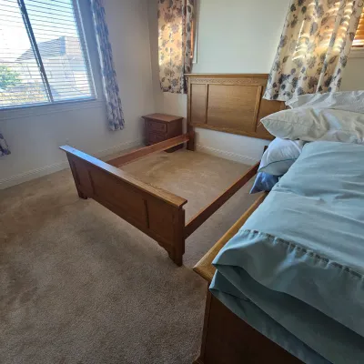 Sale Photo Thumbnail #74: Traditional oak bed frame with paneled headboard and footboard, alongside a matching nightstand in a bedroom setup.